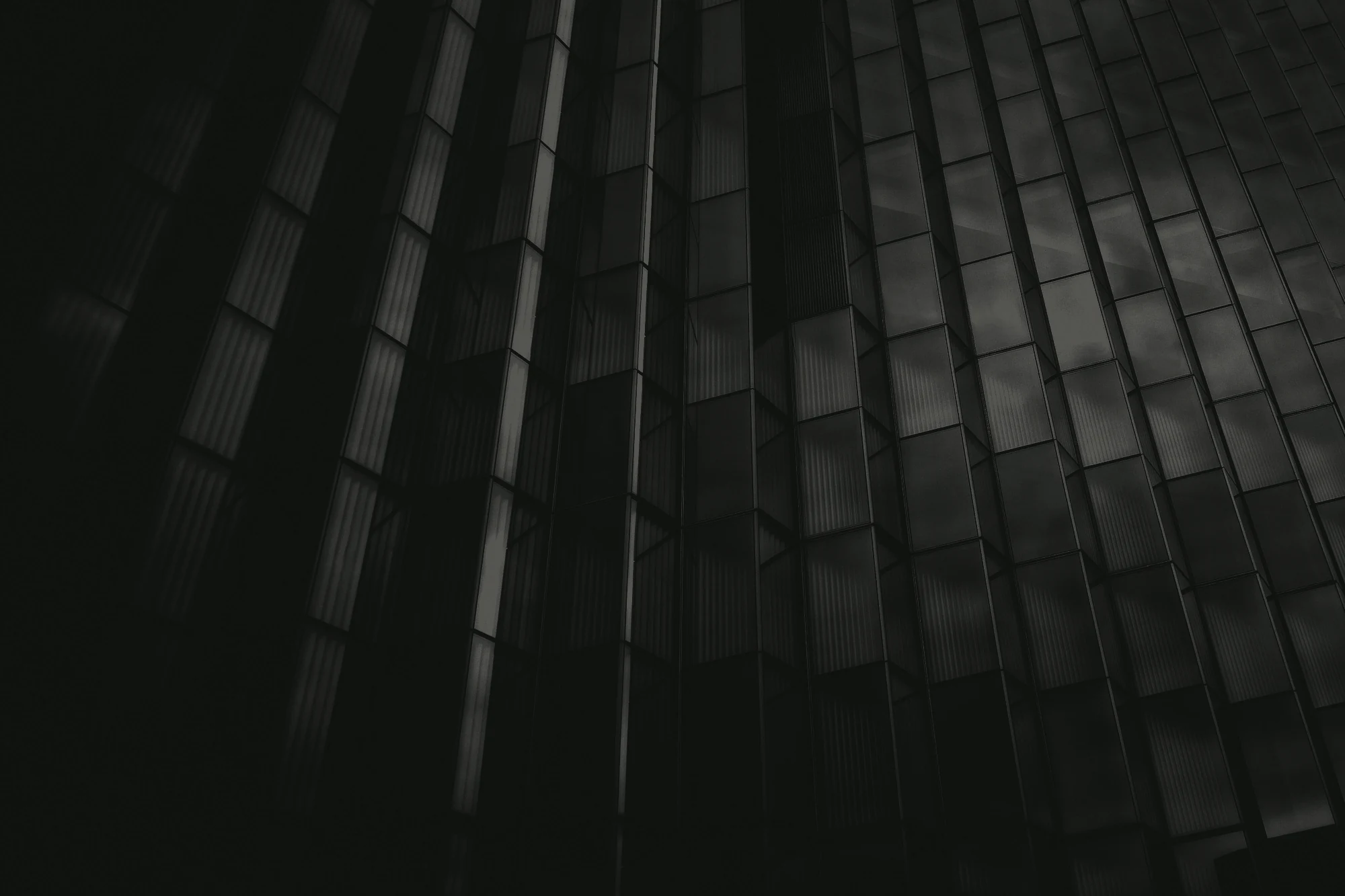 The dark glass facade of a commercial tower, seen from below